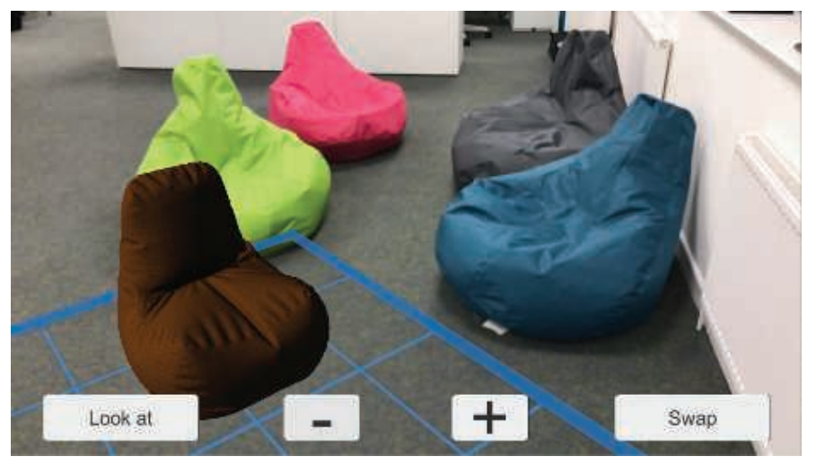 图21.2：来自ARKit的图片。它可以检测到地面，并以蓝色网格进行显示。其中最接近的棕色豆袋椅是一个叠加在地面上的虚拟物体。虽然它缺少阴影效果，但是这个阴影效果也是可以实现并添加到物体上的，并且可以与场景相混合。